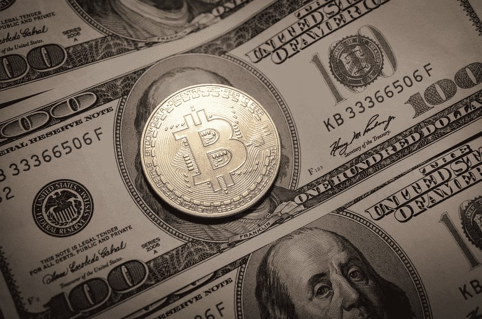 أوراق نقدية من فئة مئة دولار على إحداها قطعة نقدية ذهبية تمثل عملة بيتكوين